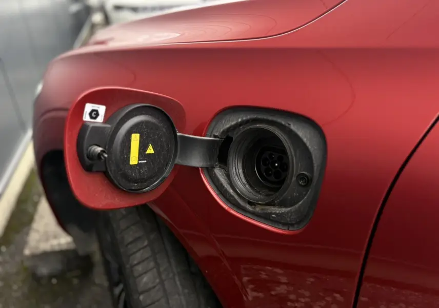 Prise de recharge ouverte côté gauche arrière d’un Volvo XC60 rouge fusion 2024 hybride rechargeable.