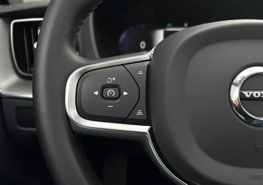 Gros plan sur la partie gauche du volant noir du Volvo XC60 T6 AWD PHEV 2024 avec commandes de régulateur de vitesse.