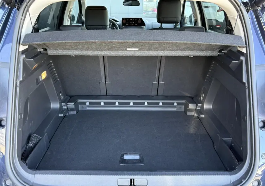 Coffre ouvert vu de l'arrière d'un Citroën C5 Aircross Hybrid bleu Eclipse avec cache-bagages et sièges arrière visibles.