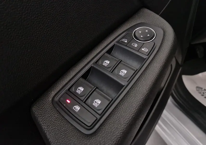 Gros plan sur les commandes de lève-vitres et rétroviseurs côté conducteur d'une Renault Clio V gris platine 2021.