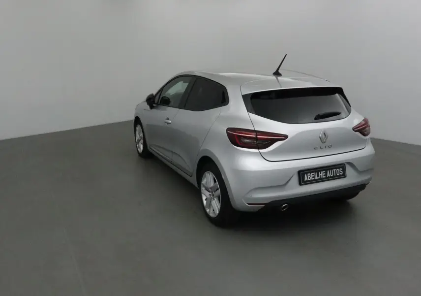 Renault Clio V gris platine vue 3/4 arrière côté gauche dans un studio avec vitres teintées et antenne toit.