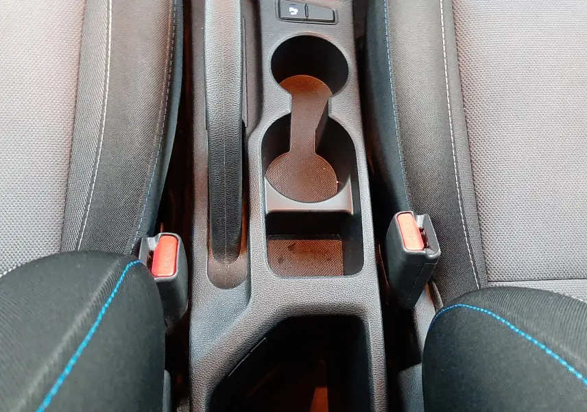 Vue plongeante sur la console centrale noire de la Hyundai i20 2016, avec porte-gobelets et frein à main entre sièges tissu gris.