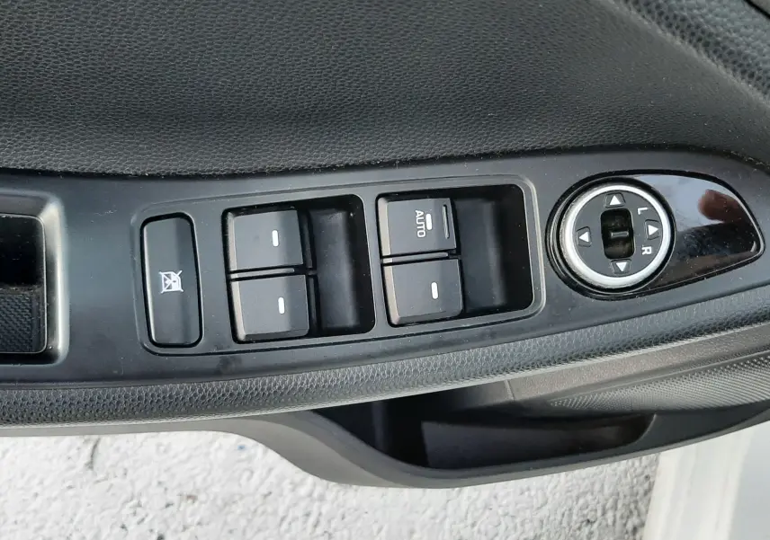 Gros plan sur la commande des vitres et rétroviseurs côté conducteur d'une Hyundai i20 blanche, version UEFA EURO 2016.