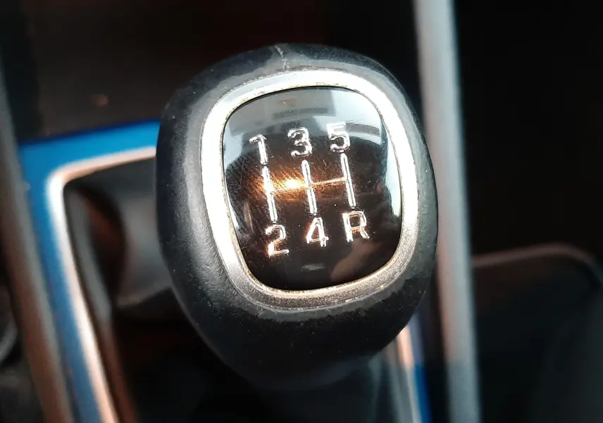 Gros plan sur le levier de vitesse manuel noir de la Hyundai i20 blanche, montrant les chiffres des rapports.