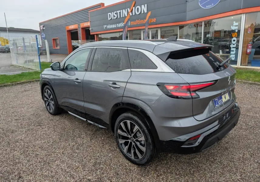 Vue 3/4 arrière droit du Renault Austral gris avec jantes alliage noires et toit noir, stationné devant un showroom Distinxion.