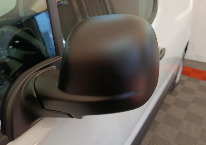 Gros plan sur le rétroviseur noir côté conducteur du Peugeot Partner blanc, vue latérale avant droite.