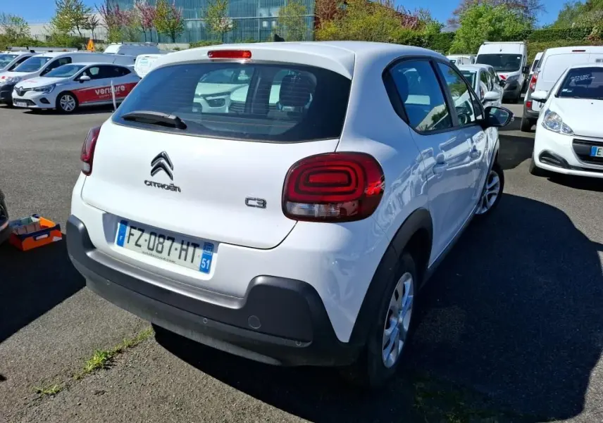 Citroën C3 Société blanc vue 3/4 avant droit sur parking avec plusieurs utilitaires en arrière-plan.