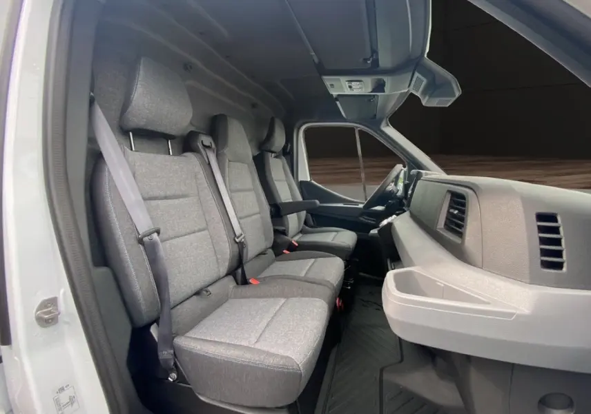 Intérieur du Renault Master blanc vu côté passager, montrant les sièges gris et le tableau de bord moderne.