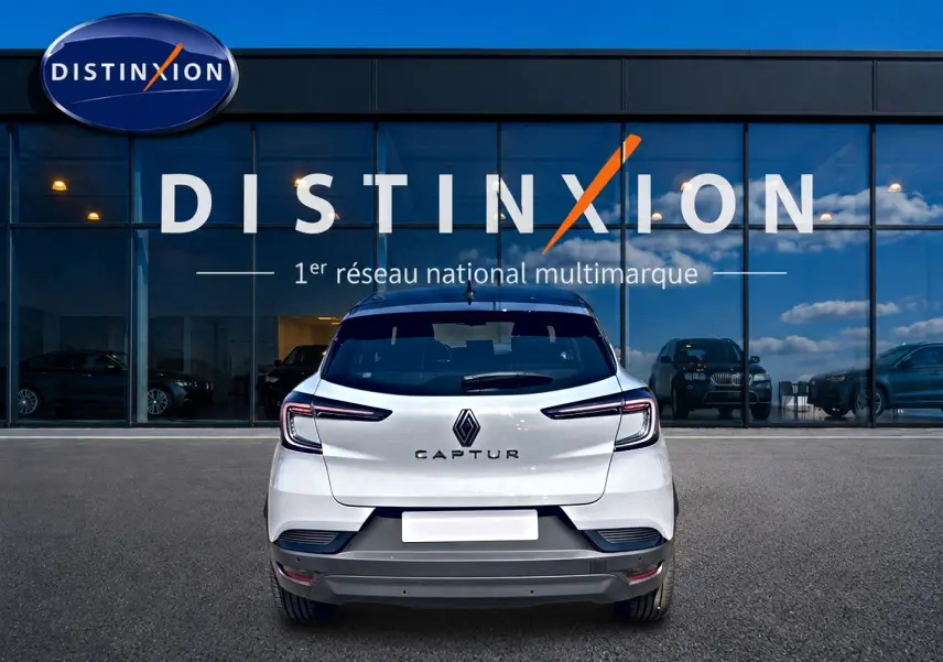 Vue arrière d'un Renault Captur 2026 blanc avec toit noir, garé devant une vitrine Distinxion.