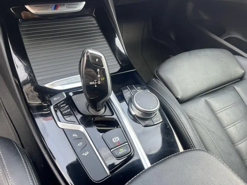 Vue rapprochée de la console centrale noire brillante avec levier de vitesses automatique et cuir Vernasca noir du BMW X3 M40iA 2019.