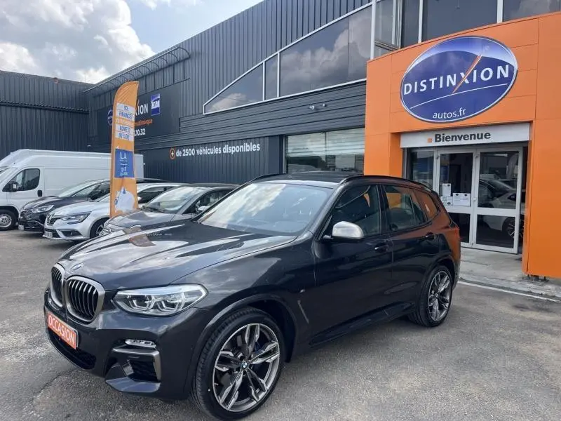 BMW X3 M40iA Sophistograu métallisé vue 3/4 avant droit avec jantes 21 pouces devant un concessionnaire Distinxion