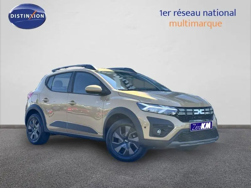Vue 3/4 avant droite d'une Dacia Sandero Stepway beige Safari avec barres de toit et jantes alliage.
