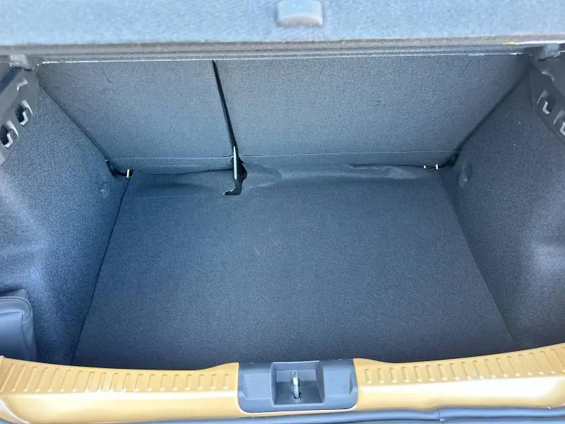 Coffre spacieux de la Dacia Sandero beige Safari 2025, vue intérieure depuis l'arrière avec banquette rabattable visible.
