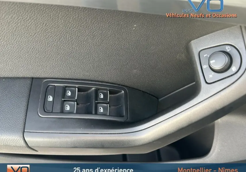 Gros plan sur les commandes de lève-vitres et réglage des rétroviseurs côté conducteur du SEAT Ateca bleu foncé 2019.