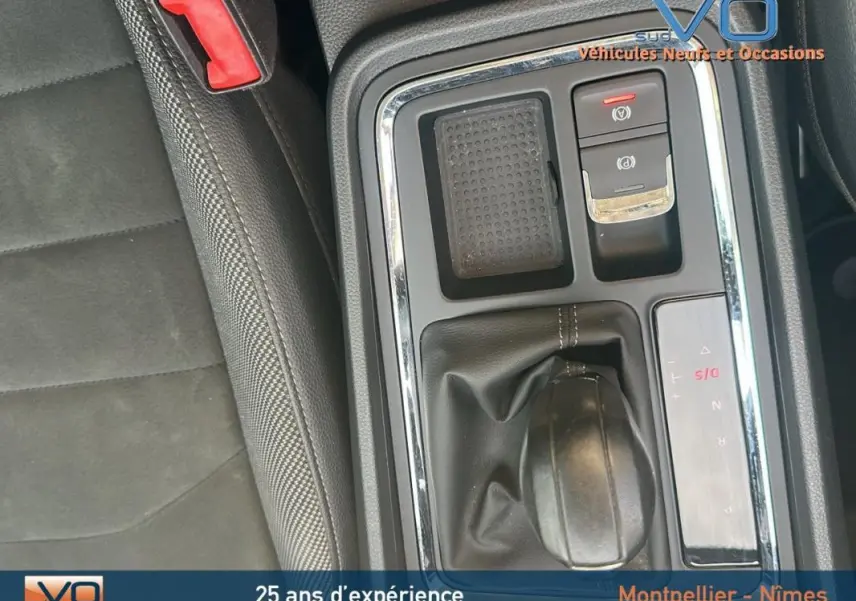 Gros plan sur la console centrale et levier de vitesse du SEAT Ateca bleu foncé, avec accoudoir et sellerie noire.