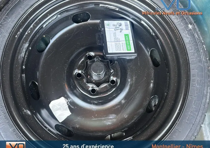 Gros plan sur la roue de secours noire du SEAT Ateca bleu foncé, avec étiquette et marquages visibles sur le pneu.