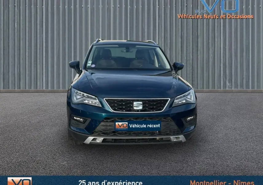 Vue frontale d'un SEAT Ateca bleu foncé 2019 avec calandre chromée et phares LED allumés.