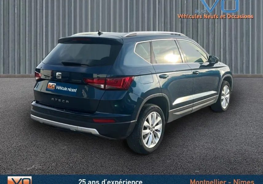 Vue 3/4 arrière droite d'un SUV SEAT Ateca bleu foncé avec jantes alliage et barres de toit argentées.