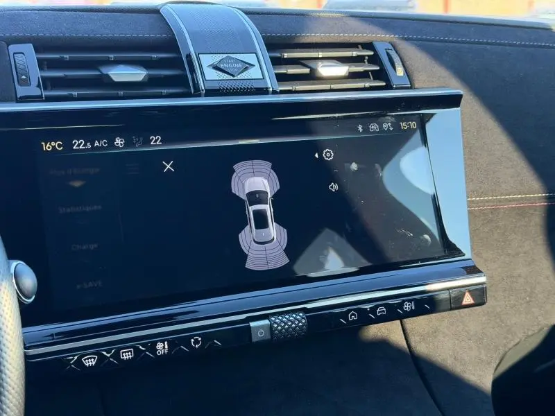 Écran tactile central du DS7 E-TENSE 2024 en gros plan, affichant l'aide au stationnement, intérieur noir avec surpiqûres jaunes.