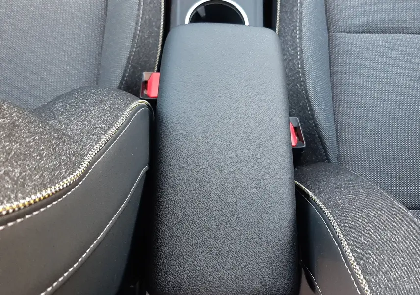 Vue plongeante sur l'accoudoir central noir et les sièges tissu gris du Renault Captur 2024 intérieur.