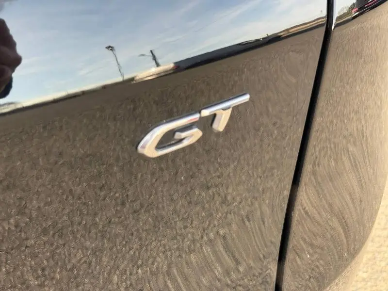 Gros plan sur l’inscription GT sur la porte côté droit d’un Peugeot 3008 2024 en Bleu Célèbes avec toit noir.
