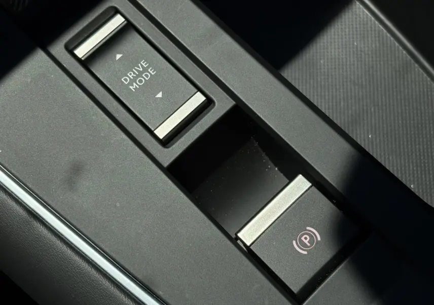 Gros plan sur la console centrale noire du Citroën C5 Aircross Hybrid avec boutons Drive Mode et frein de stationnement électrique.