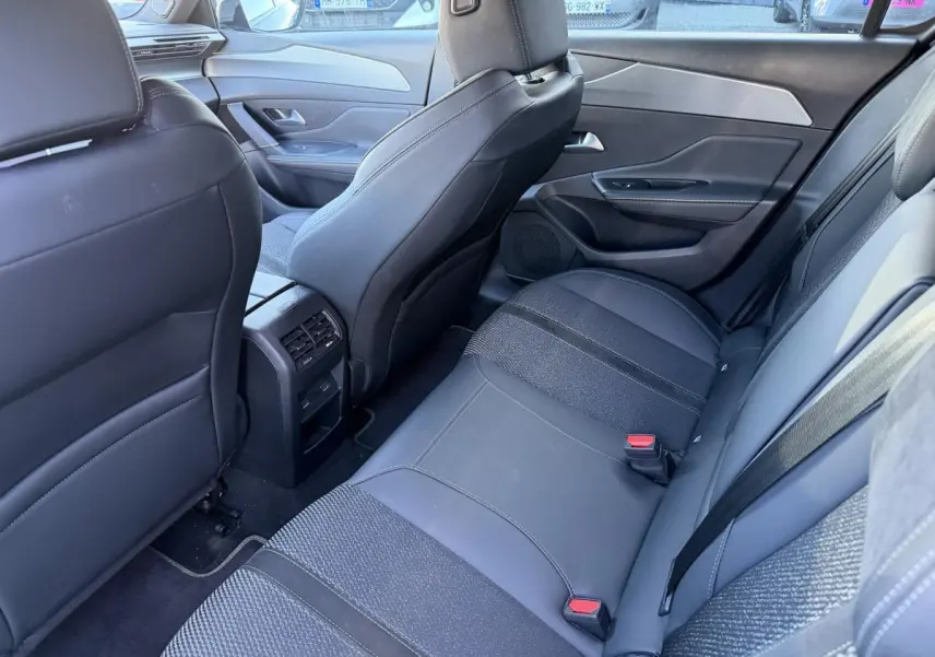 Vue arrière intérieure de la Peugeot 308 2024, sièges noirs en tissu et TEP avec prises USB C et aérateurs centraux.