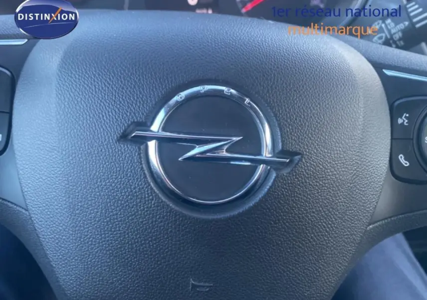 Gros plan sur le volant cuir noir de l'Opel Crossland 2022 avec logo Opel central et commandes multifonctions visibles.