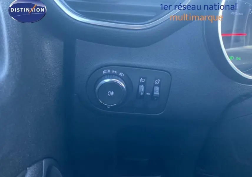 Gros plan sur la commande des feux et réglages d’éclairage côté gauche du tableau de bord d’un Opel Crossland gris foncé 2022.