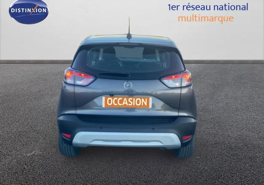Vue arrière d'un Opel Crossland gris foncé 2022 avec feux allumés sur fond neutre.
