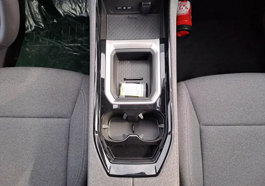 Vue plongeante sur la console centrale noire brillante du Renault Austral gris schiste, entre sièges tissu gris.