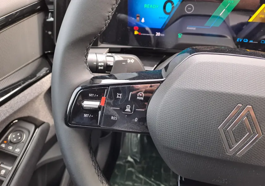 Vue rapprochée du volant noir du Renault Austral 2025, avec commandes de régulateur et tableau de bord numérique en arrière-plan.