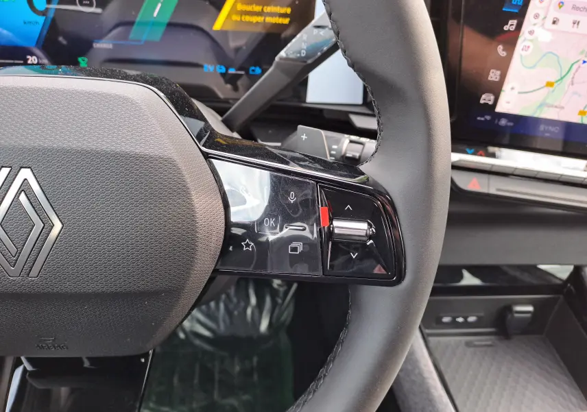 Gros plan sur le volant noir du Renault Austral 2025 avec commandes tactiles et tableau de bord numérique en arrière-plan.