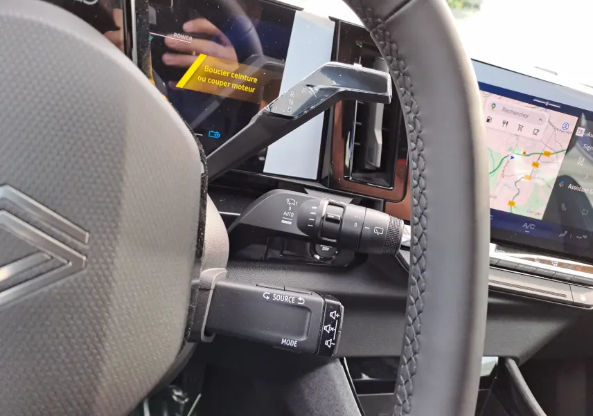 Gros plan sur le volant et la console centrale du Renault Austral gris schiste, avec écran tactile et commandes au volant visibles.