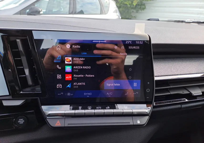 Vue rapprochée de l'écran tactile central du Renault Austral 2025, affichant les options radio et commandes climatisation.