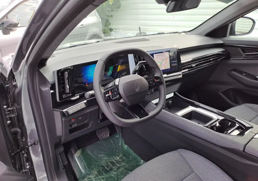 Intérieur noir du Renault Austral 2025, vue côté conducteur montrant volant, tableau de bord numérique et écran central tactile.
