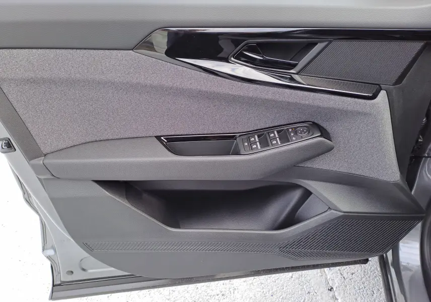 Vue rapprochée de la porte avant gauche du Renault Austral gris schiste, avec commandes électriques et garniture tissu noir.