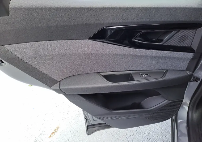 Vue rapprochée de la porte avant gauche du Renault Austral gris schiste, avec garniture tissu gris et commandes de vitre.