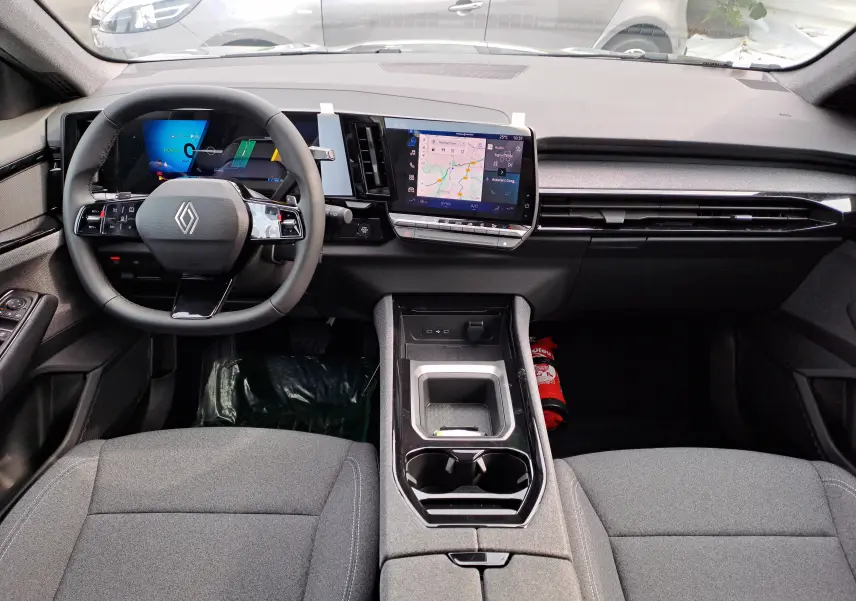 Vue intérieure du tableau de bord du Renault Austral gris schiste, avec volant multifonctions et écran tactile central affichant la navigation.