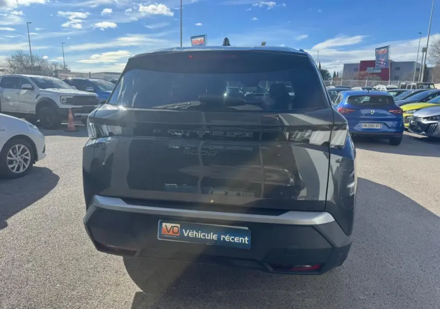 Vue arrière d’un Peugeot 5008 Hybrid gris 2025 avec feux arrière LED et jantes alliage 19 pouces visibles en extérieur.
