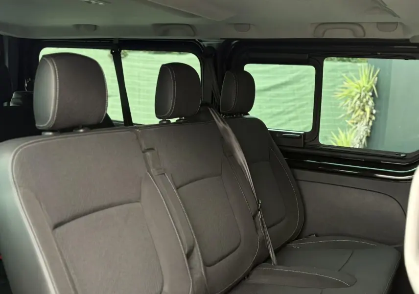 Vue intérieure côté droit sur les sièges noirs du Nissan Primastar 2025 avec vitres latérales coulissantes ouvertes.