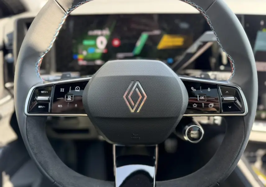 Vue rapprochée du volant textile noir avec insert Alcantara et logo Renault au centre du Renault Austral 2026.