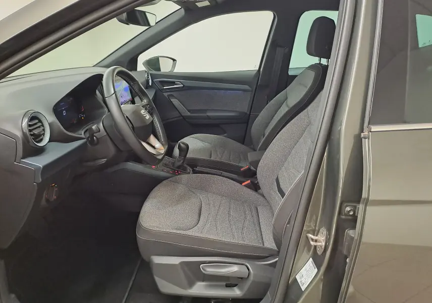 Vue intérieure côté conducteur du SEAT Arona gris falaise 2024, montrant les sièges avant et le tableau de bord moderne.