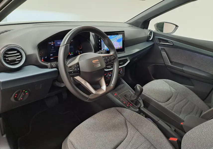 Vue intérieure côté conducteur du SEAT Arona 2024, avec tableau de bord numérique et sellerie tissu gris.