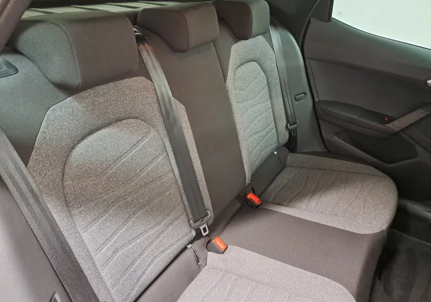 Vue intérieure des sièges arrière du SEAT Arona 2024, tissu gris clair et foncé avec ceintures de sécurité visibles.
