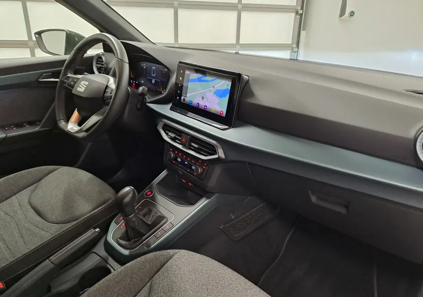 Vue intérieure côté conducteur du SEAT Arona 2024 avec tableau de bord moderne et écran tactile central.