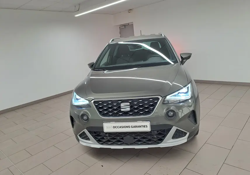 Vue avant d'un SEAT Arona gris falaise 2024 avec phares LED allumés et bouclier avant spécifique Pack Adventure Design.