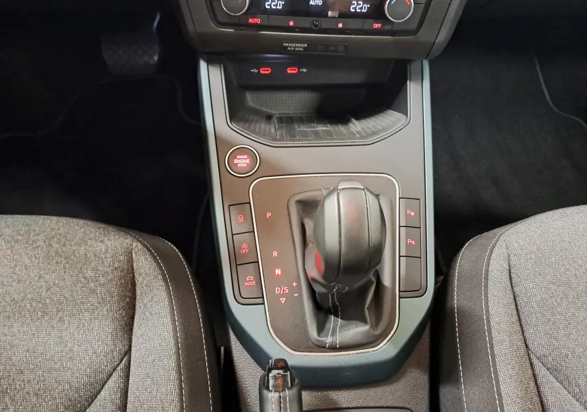Vue plongeante sur la console centrale du SEAT Arona 1.5 TSI 150 DSG7 XPERIENCE avec levier de boîte auto et boutons lumineux.