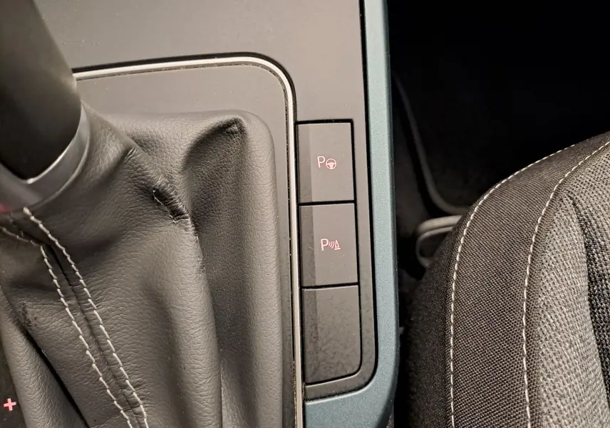 Gros plan sur la console centrale du SEAT Arona 2024, montrant les boutons d’aide au stationnement et la sellerie noire.