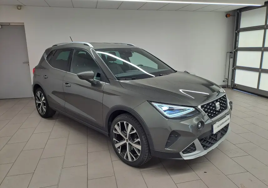 SEAT Arona 1.5 TSI 150 DSG7 XPERIENCE gris falaise en 3/4 avant droit, avec jantes alliage 18'' et éclairage LED distinctif.